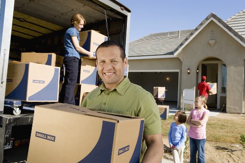 Professional movers carrying packed boxes and furniture